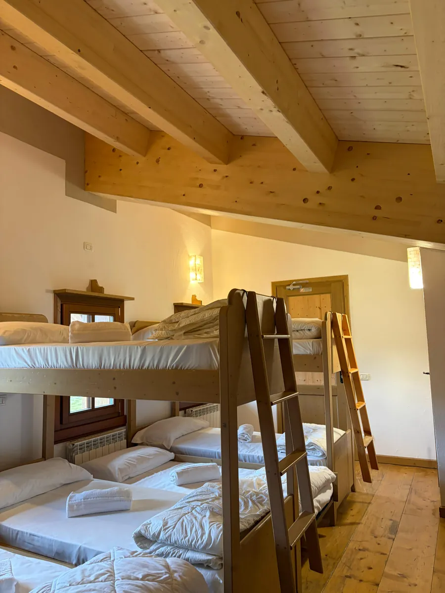 Camerata con letti a castello sotto il soffitto in travi di legno chiaro