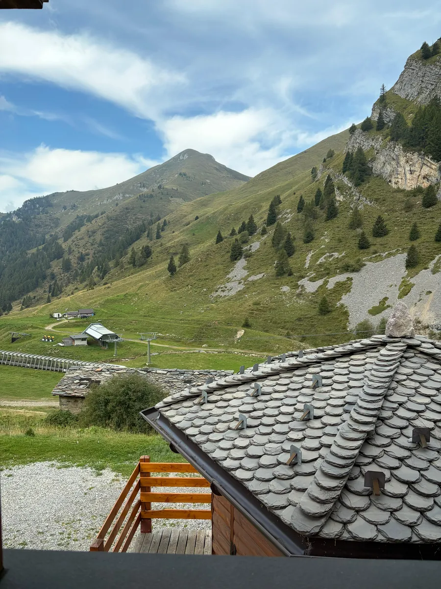 Il tetto in piode del rifugio e, dietro, la valle con la seggiovia e le cime